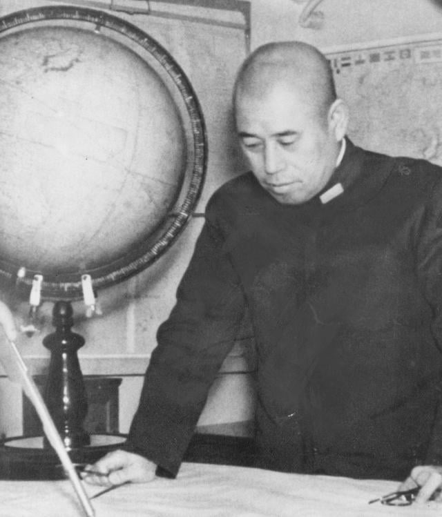 Portrait of Admiral Isoroku Yamomoto looking down at a map.