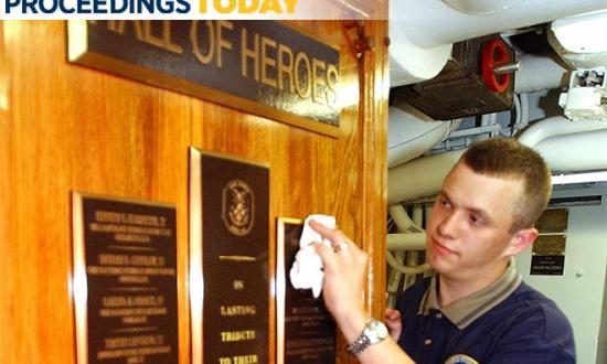 A Sailor polishes a plaque on board the USS Cole (DDG-67) 
